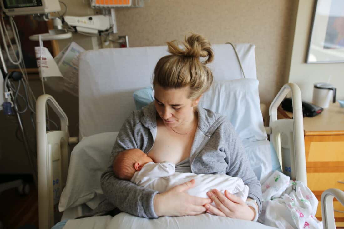 a woman breastfeeding in a hospital bed