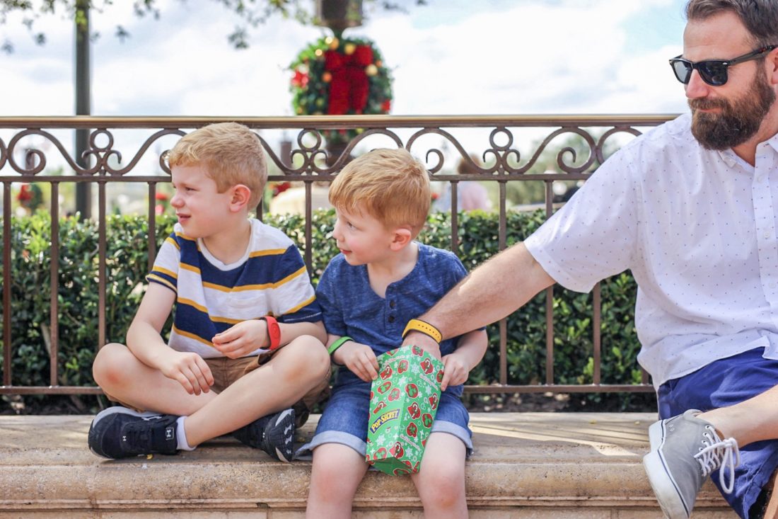 two boys and their dad eating popcorn at Disney world 