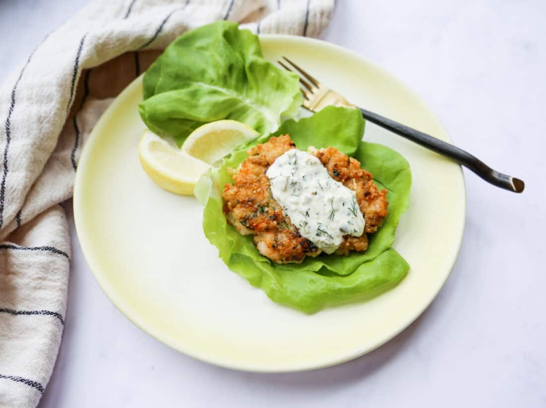 shrimp burger servd on a white plate with homemade tartar sauce