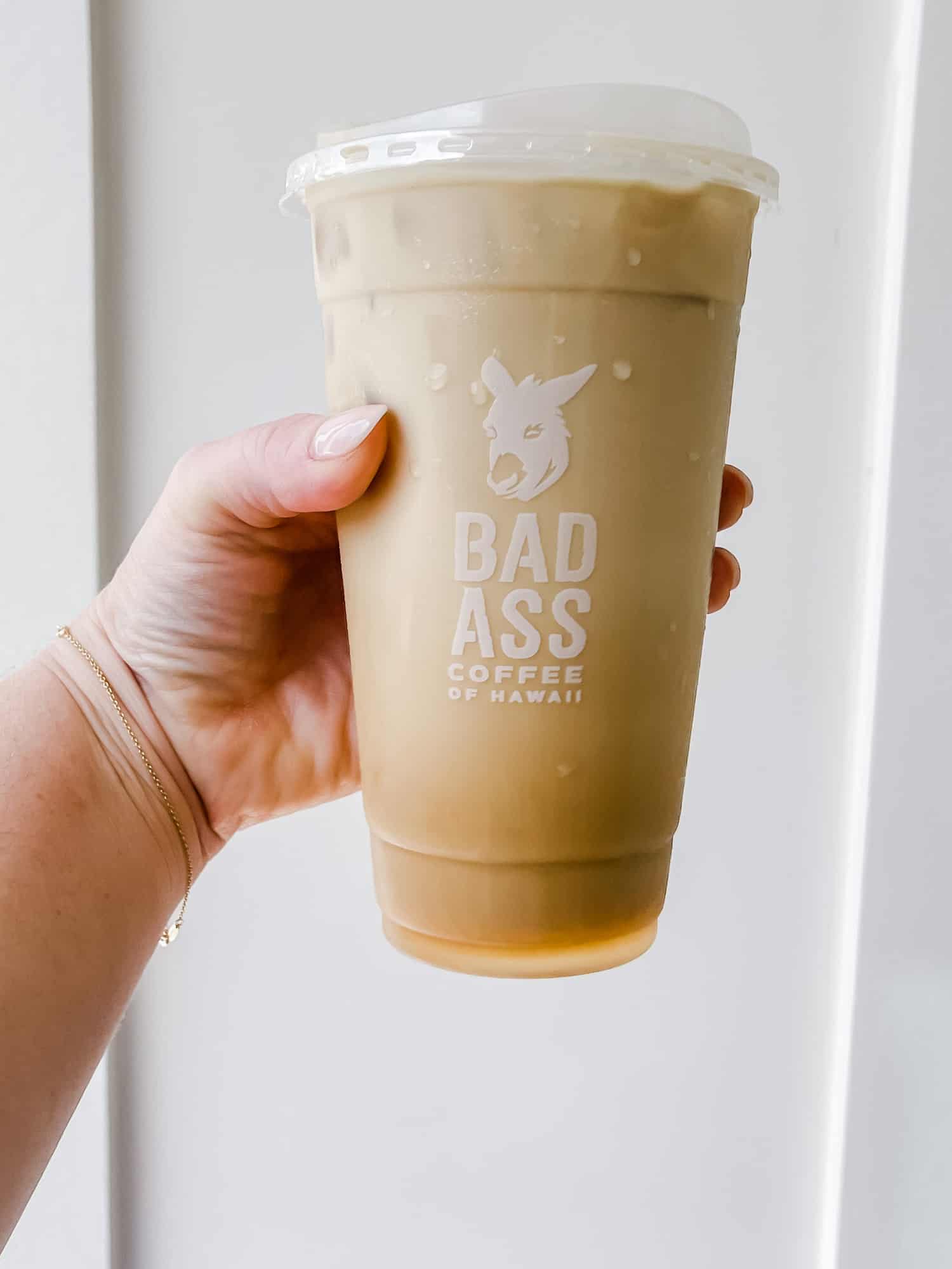 a woman's hand holding a large cup of coffee that reads "bad ass coffee" 