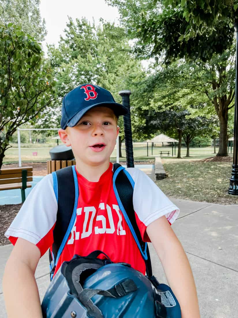 a little boy wearing a blue red sox hat