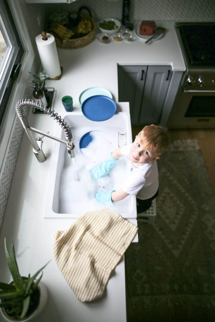 a little boy looking up washing dishes