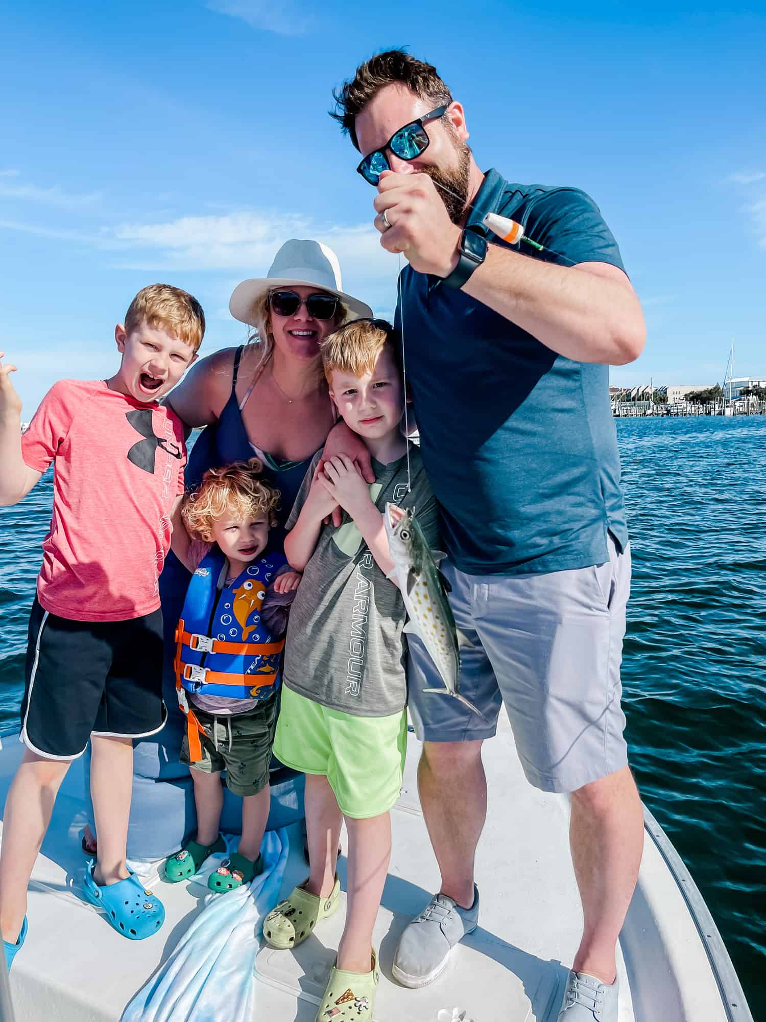 three boys, a mom, and a dad on a boat holding a fish