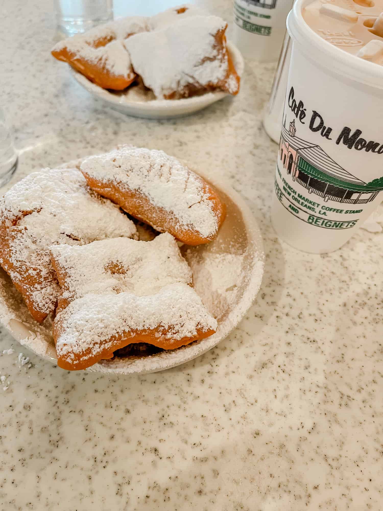 a plate of powdered sugar covered beignets