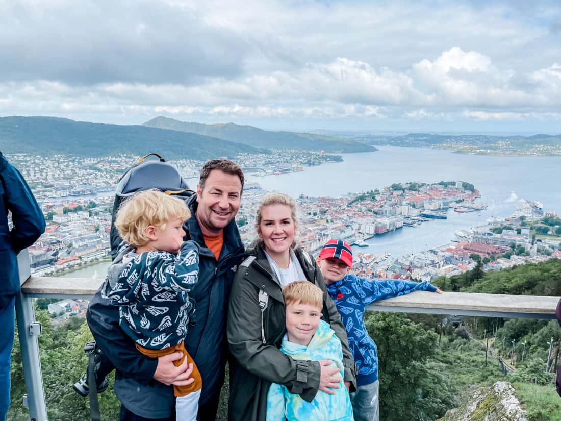 a couple with three boys posing with a view of Norway in the background