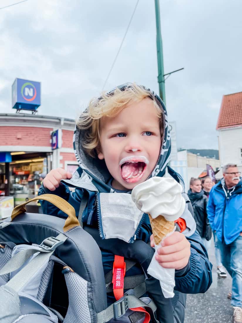 a boy holding an ice cream cone with ice cream all over his face