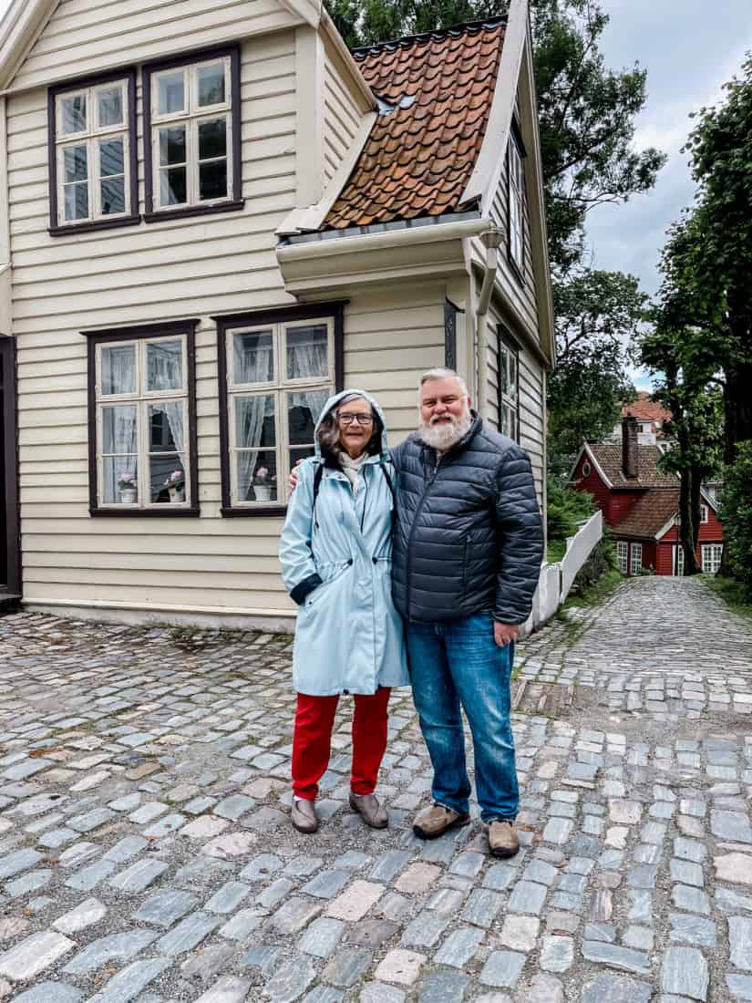 a couple posing in front of a house on a street in Norway