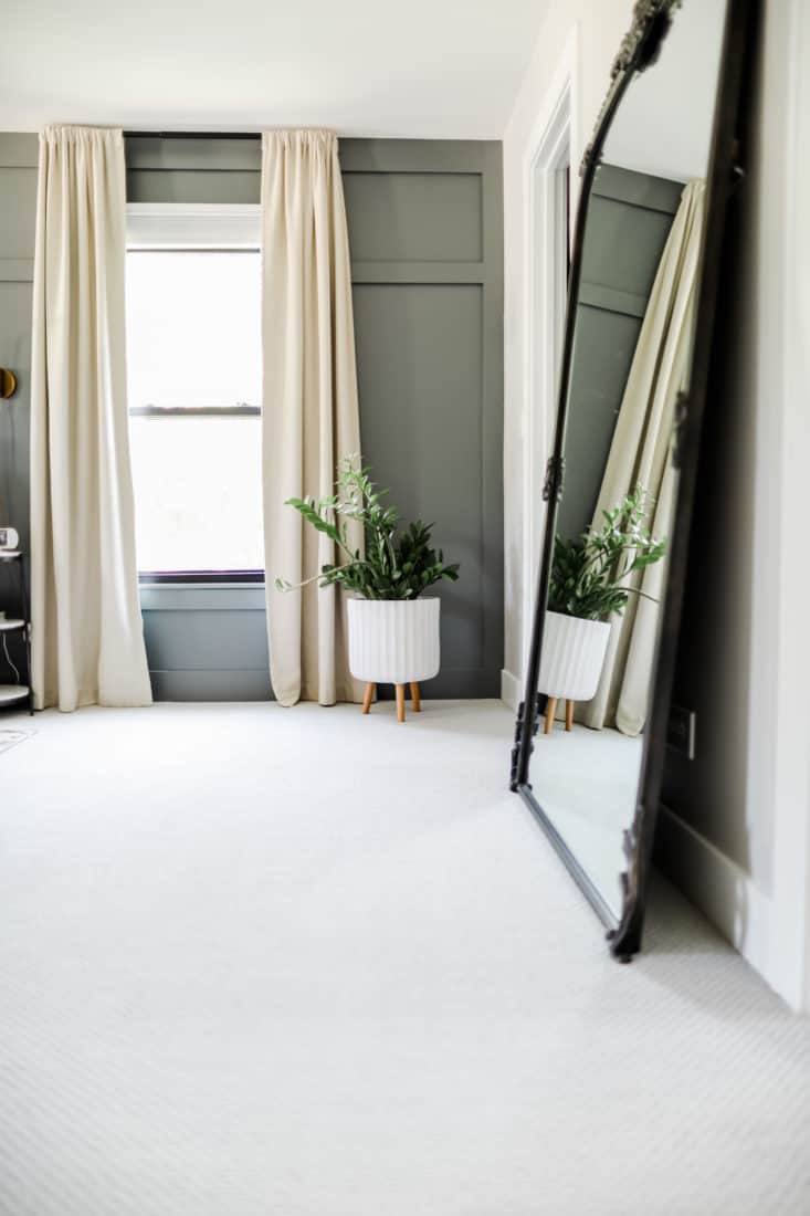 a window with floor length curtains, a plant, and a mirror