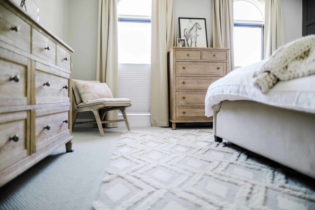 a wall of a bedroom featuring a chair, windows, and cabinet