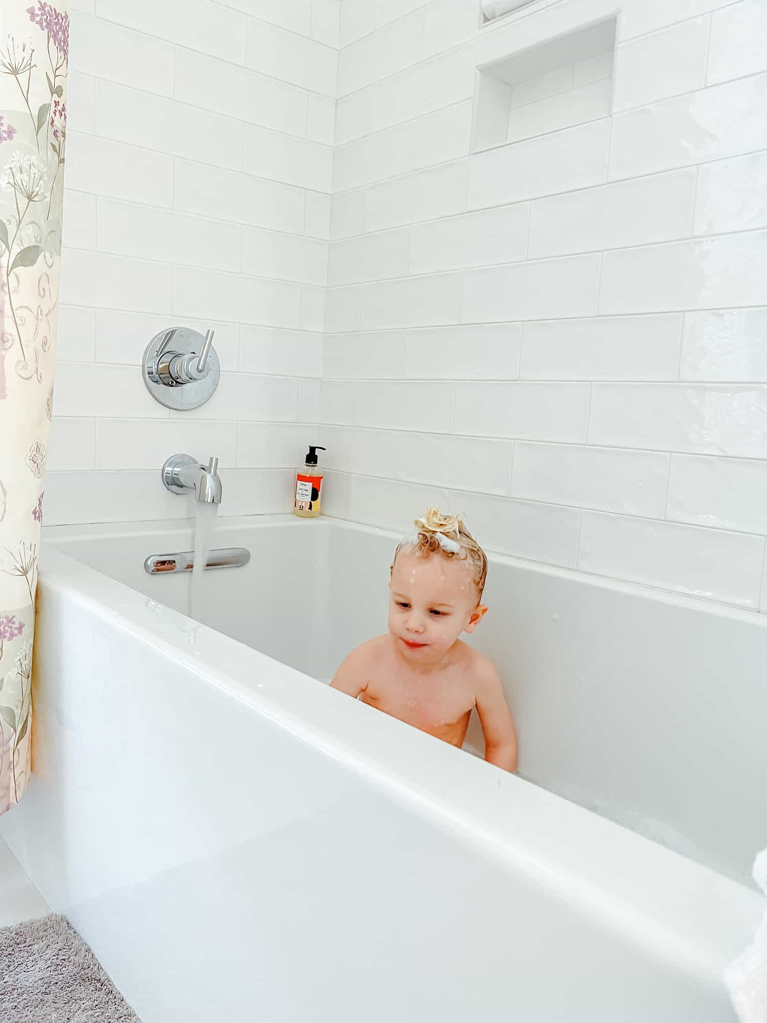 a boy in a bathtub with shampoo in his hair