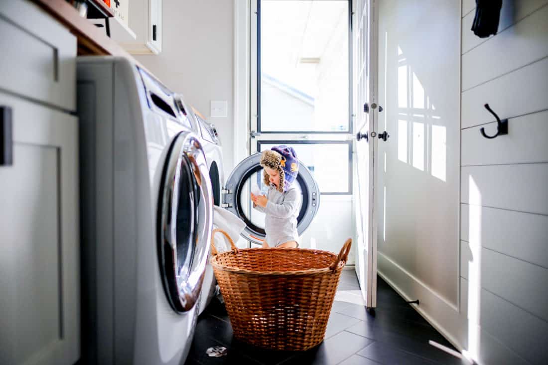 a little boy in pajamas and a winter hat in front of a washer and dryer