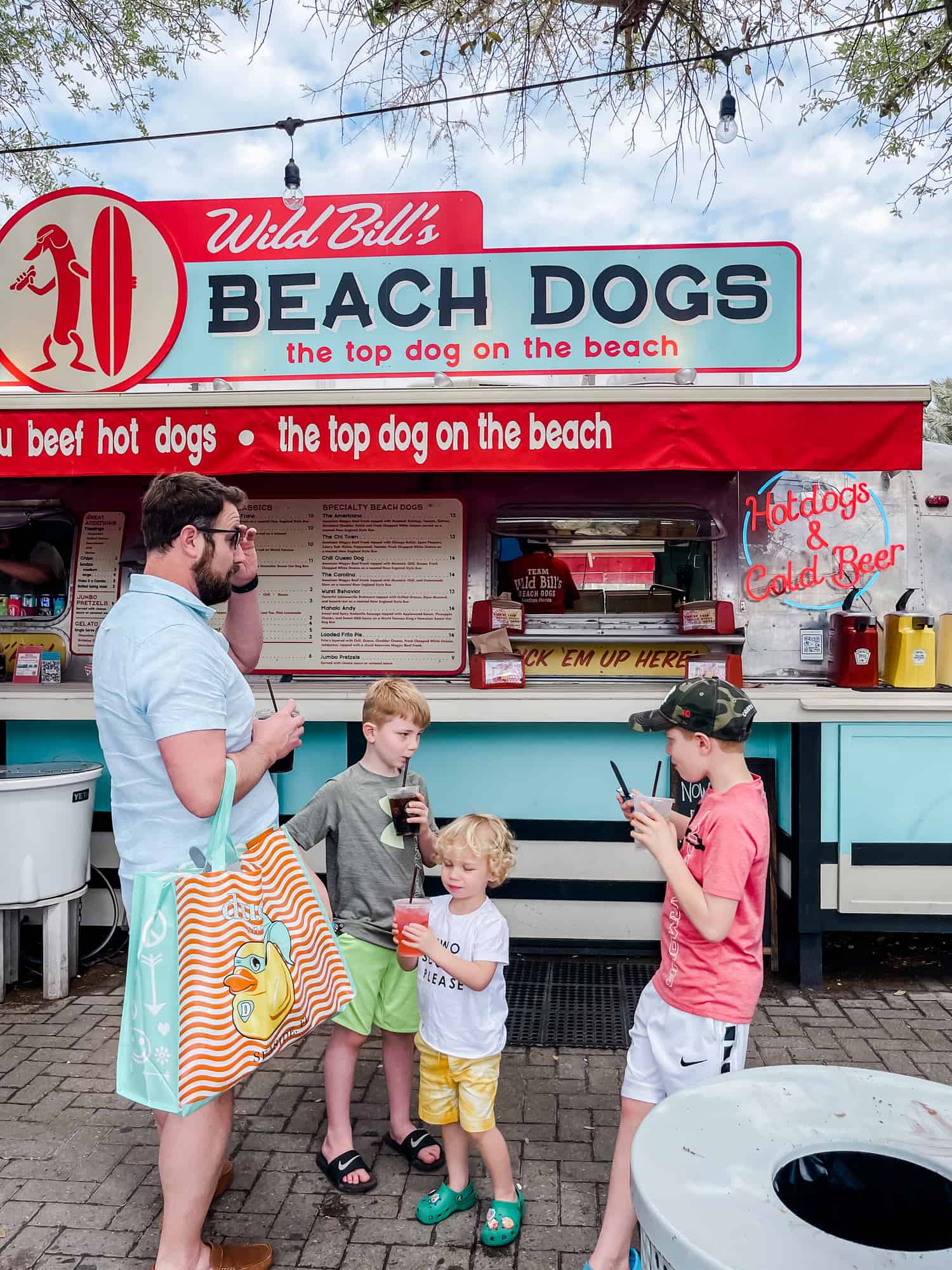 three boys and their dad standing in front of a food truck holding drinks