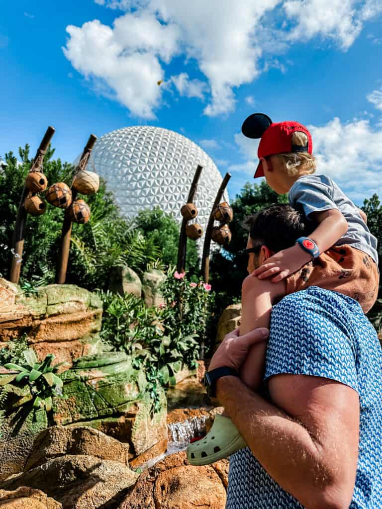 boy on top of dad's shoulders with Mickey hat at Epcot